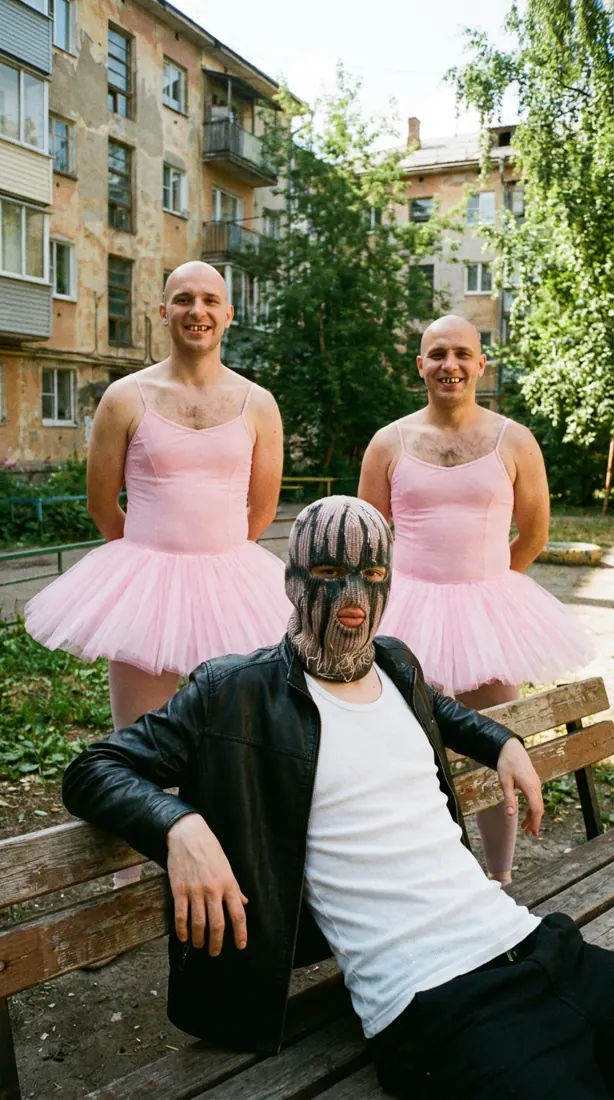 GLAKI on a bench with two men in pink tutus