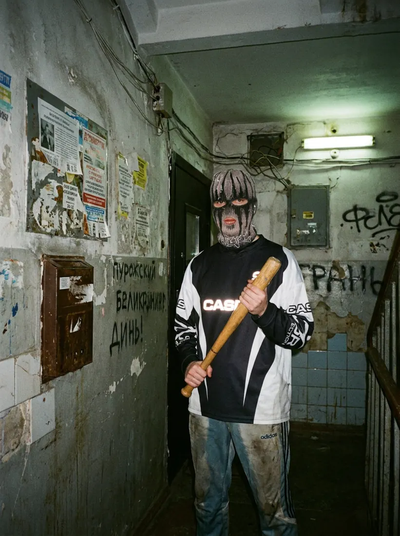 GLAKI holding a baseball bat in a run-down stairwell